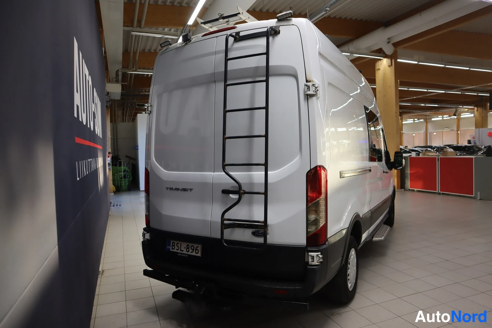 Takaa: Ford Transit -pakettiauton takaosa suoraan takaa, peräladder ja rekisteritunnus näkyvät.