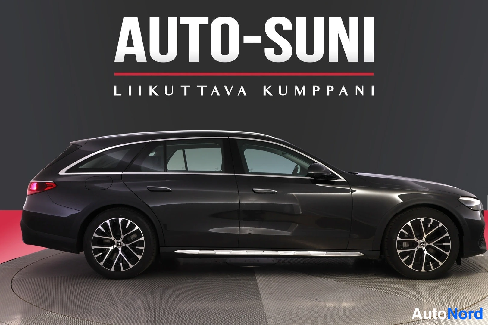 Sivulta: Mercedes-Benz farmariauto sivusta vasemmalta kuvattuna, tummansininen.