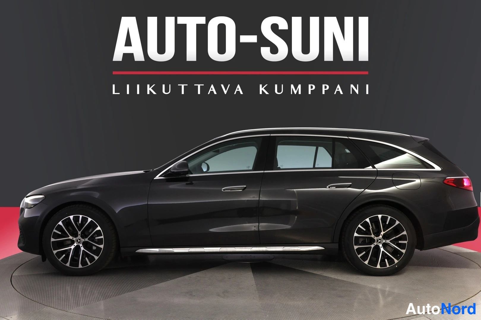 Sivulta: Mustanharmaan farmariauton sivukuva studiotauen ja punaisella taustalla, AUTO-SUNI-mainoskuvitus.