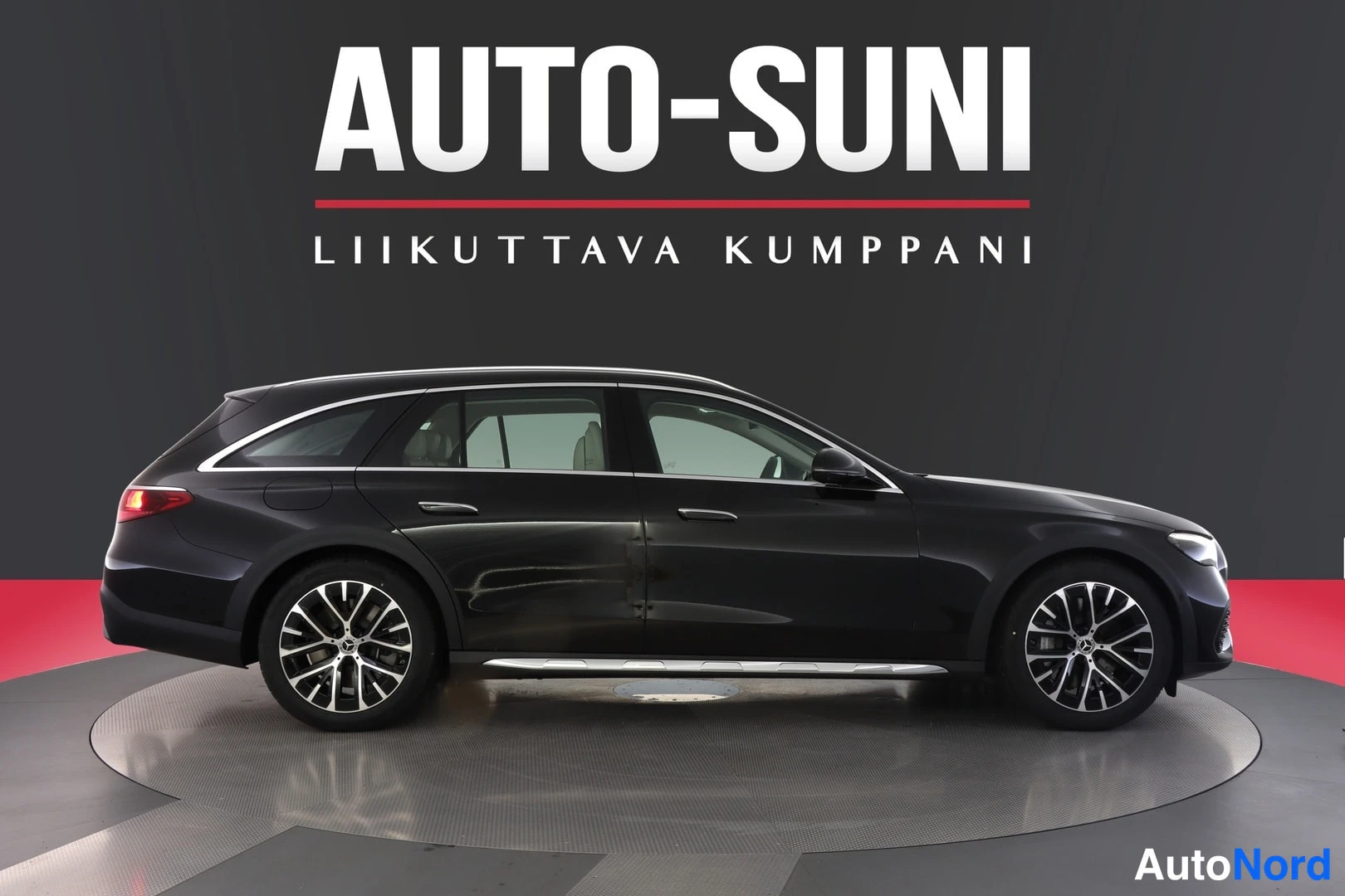 Sivulta: Mustan Mercedes-Benz E -farmarin sivukuva oikealta puolelta studio­taustaa vasten.