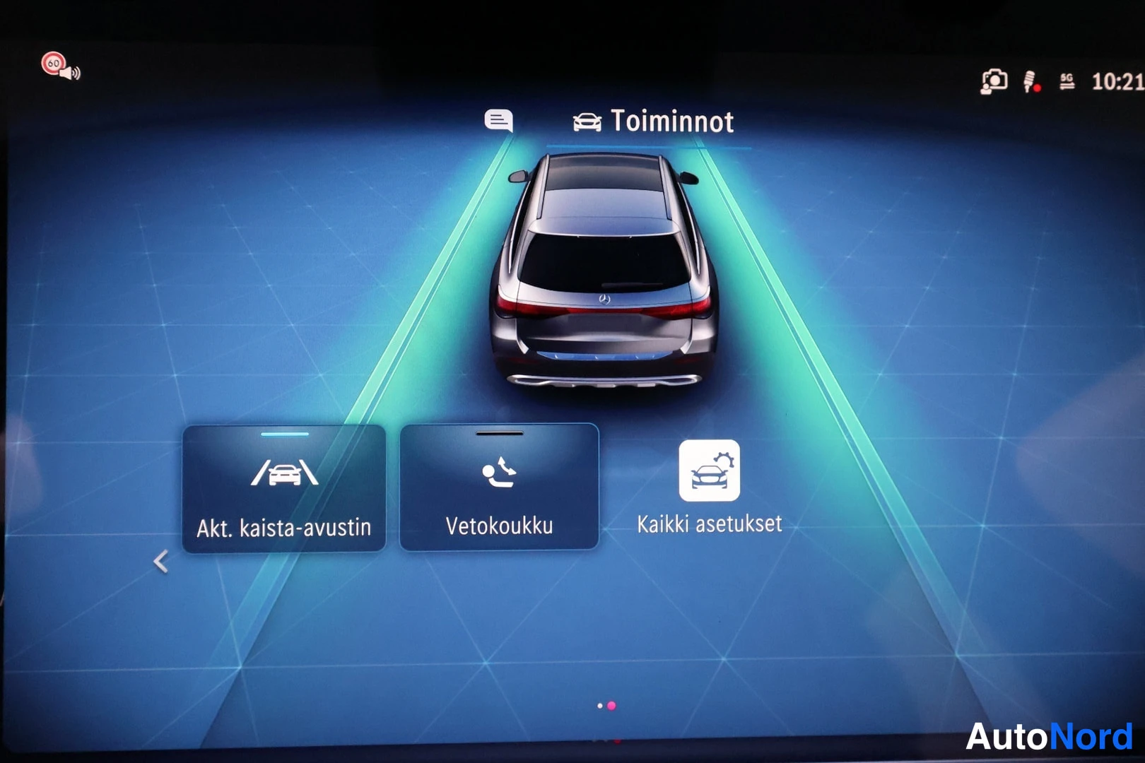 Muu: Infotainment-näytön Toiminnot-valikko, jossa takaakanasta näytettävä auto vihreillä kaista-alueilla sekä valinnat Akt. kaista-avustin, Vetokoukku ja Kaikki aset