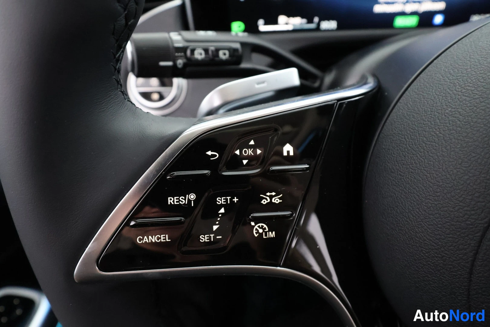 Muu: Umpikuva Mercedes-Benzin ohjauspyörän oikeasta puolesta: nappiryhmä teksteillä RES/, CANCEL, SET +, SET −, LIM, OK ja kotinappi.