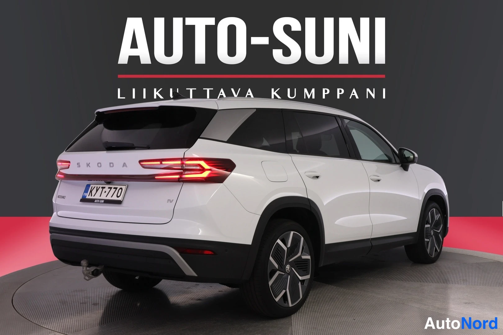 Takaviisto: Rear three-quarter view of a white Skoda Kodiaq with lit taillights and license plate.