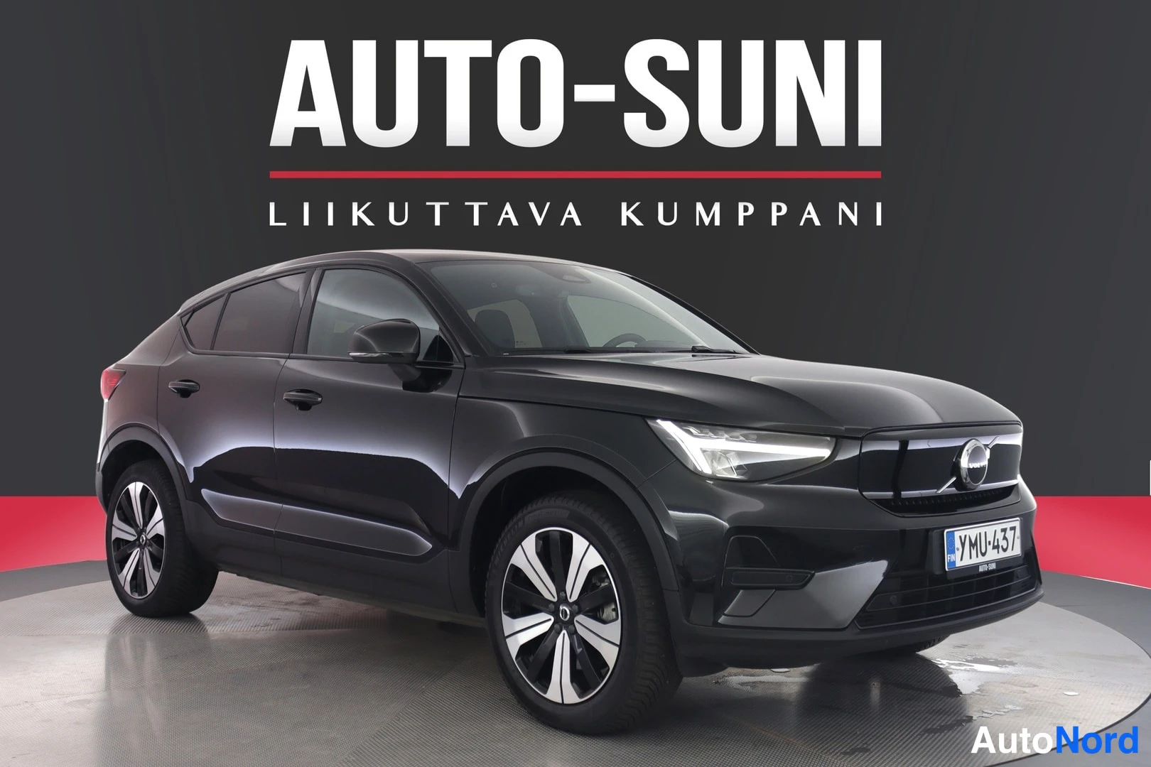 Etuviisto, nokka oikealle: Musta henkilöauto seisoa studioissa, keulanosa ja oikea kylki näkyvät, rekisteri.