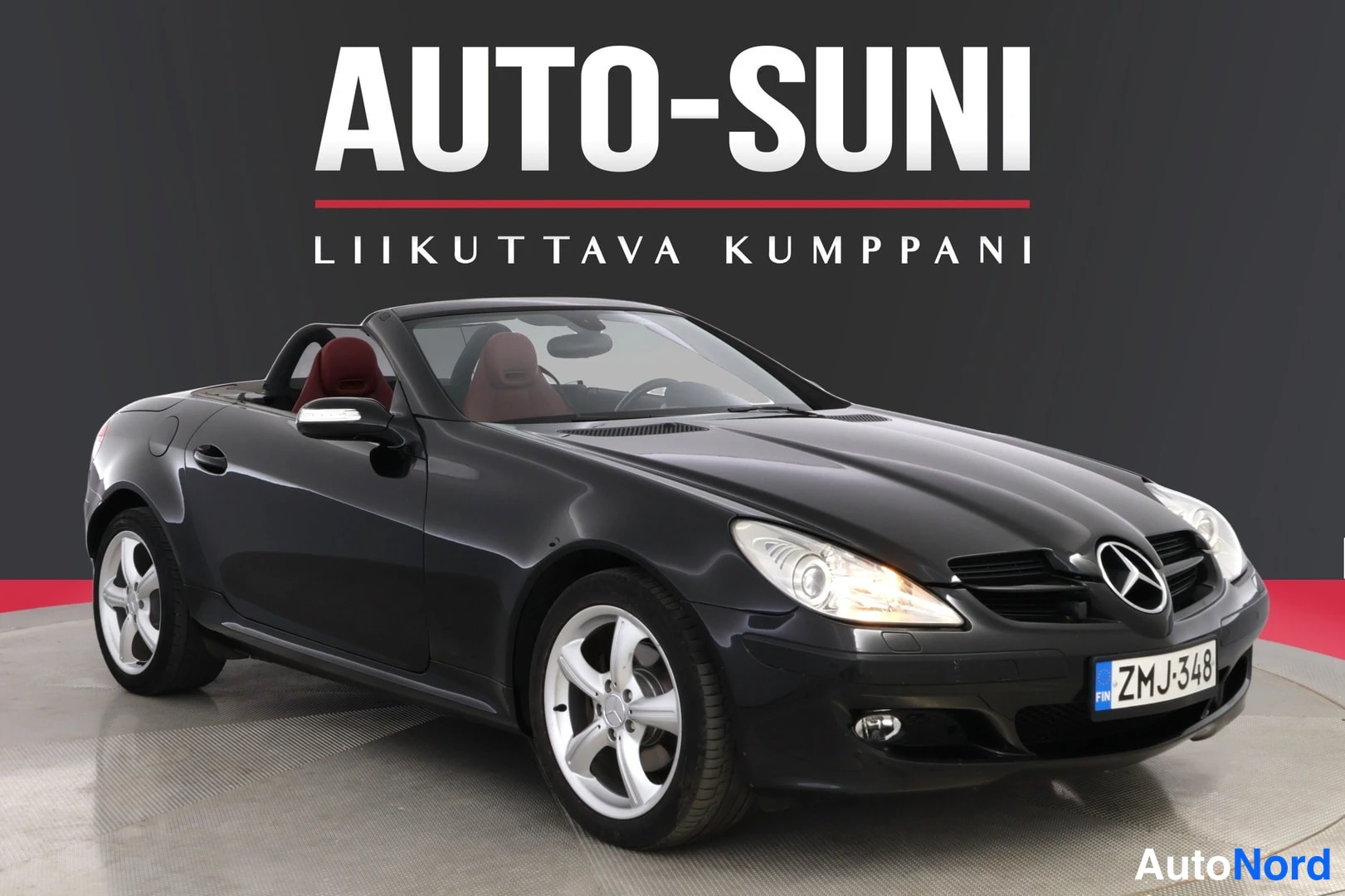 Etuviisto, nokka oikealle: Musta Mercedes-Benz SLK-avomallisetyyssä vinosti edestä vasemmalta kuvattuna, rekisterikilpi.