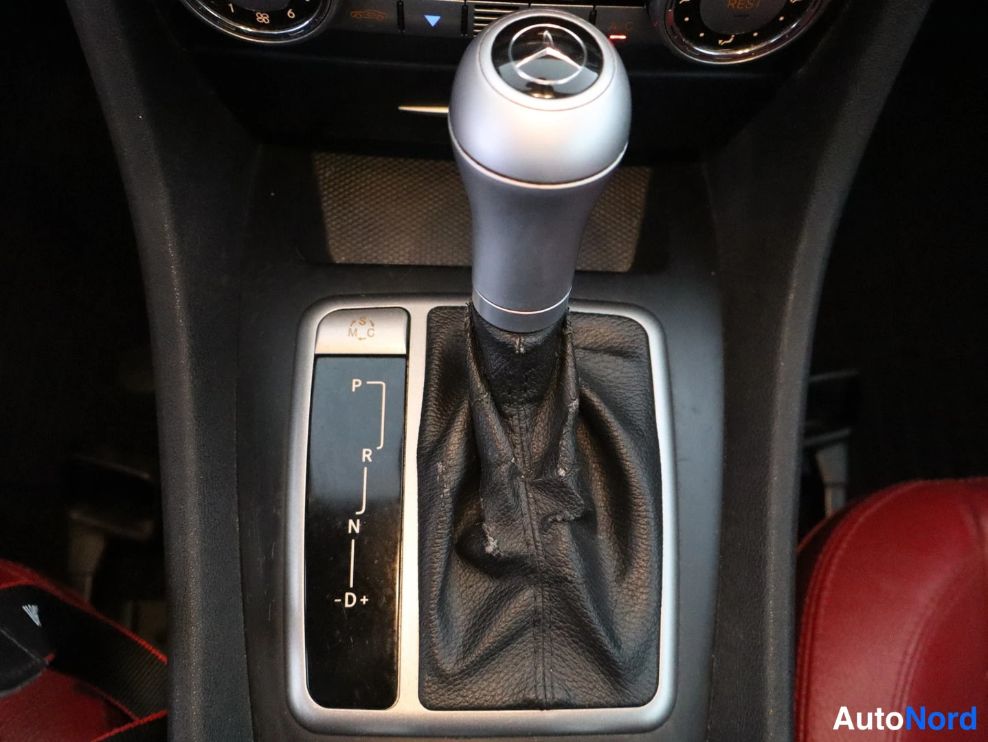 Yksityiskohta: Mercedes-tunnuksella varustettu automaattivaihteen valitsin, jonka vieressä P-, R-, N- ja D+/-merkinnät.