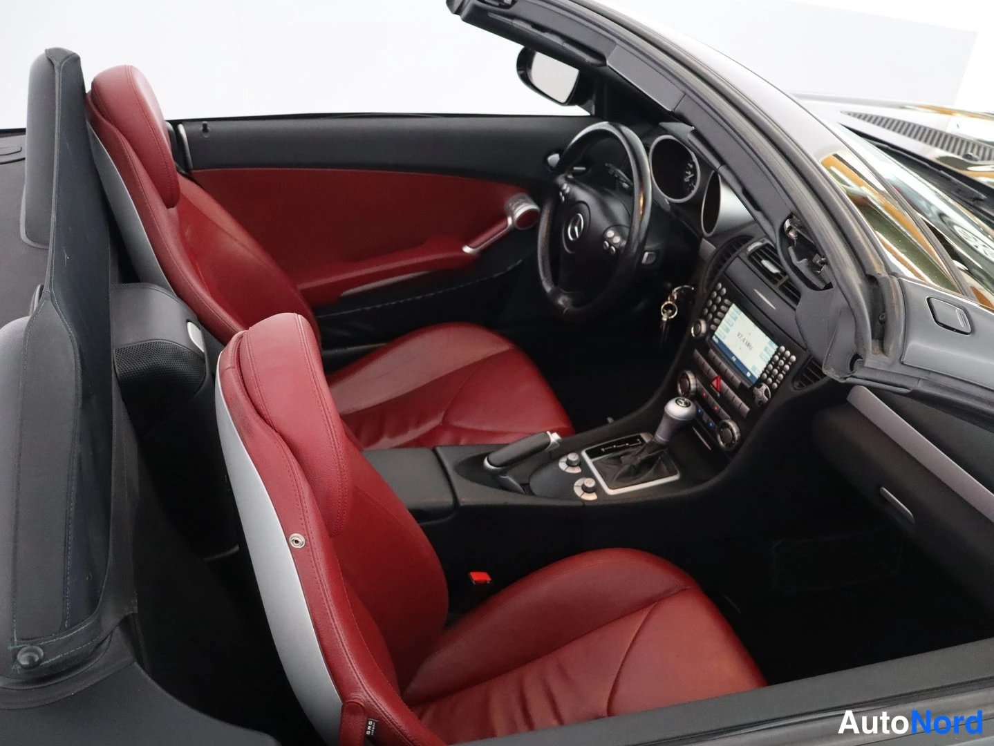 Muu: Mercedes-Benz SLK avattavalla katolla auki: sisätilat ylhäältä taakse nähtynä, punaiset nahkaistuimet ja infotainment-näyttö.