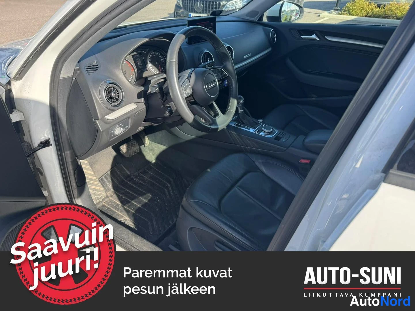 Muu: Sisäkuva autoon, musta ajohjausruutu, mittaristo ja taaksepäin kaatuva ajotila; ikkunasta näkyy voimakas taivaansininen ja valkoinen, jonka sivuojat heittävät v