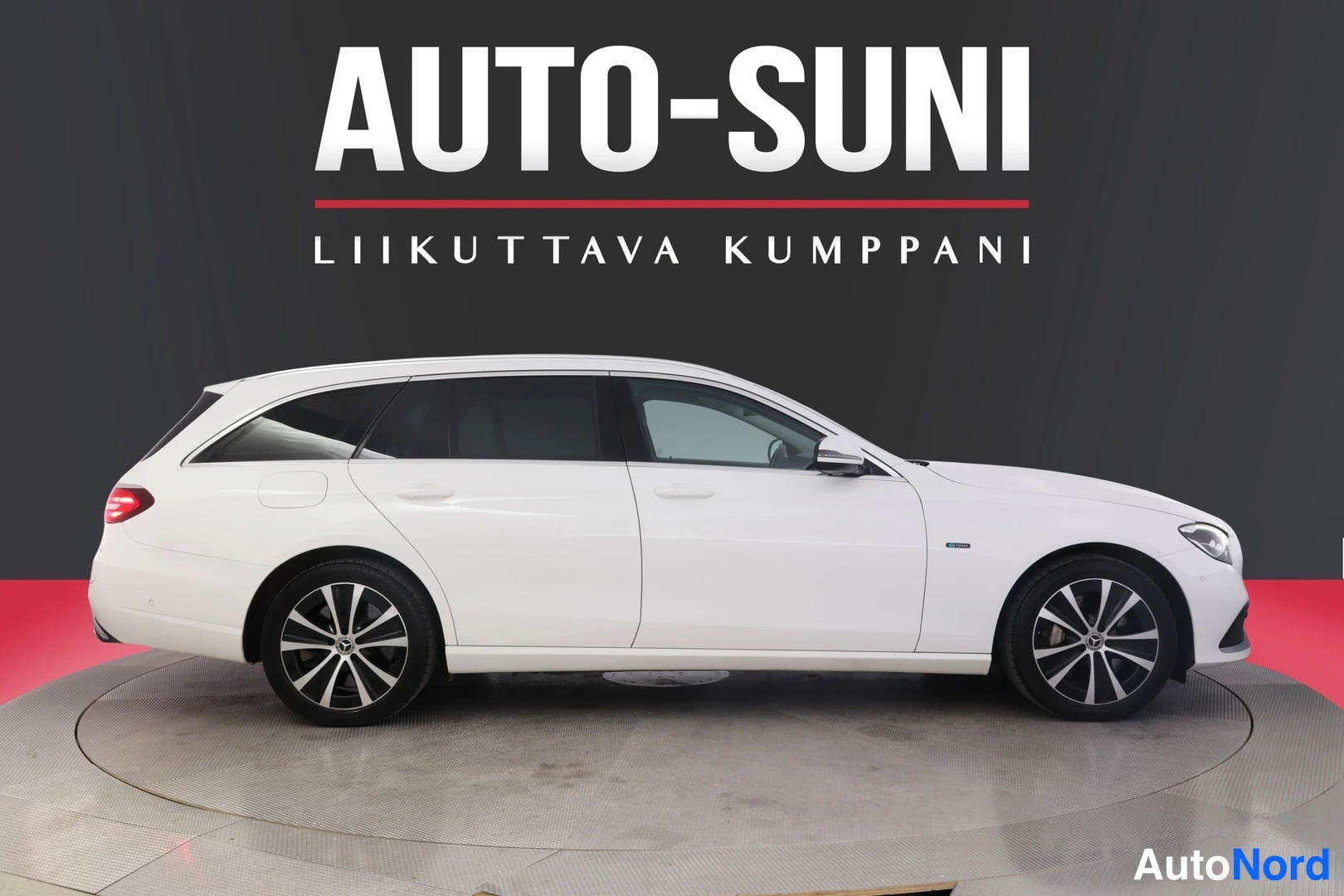 Sivulta: Valkoinen Mercedes-Benz farmari sivulta oikealle katsoen, keulan nokka kuvan oikeassa laidassa.