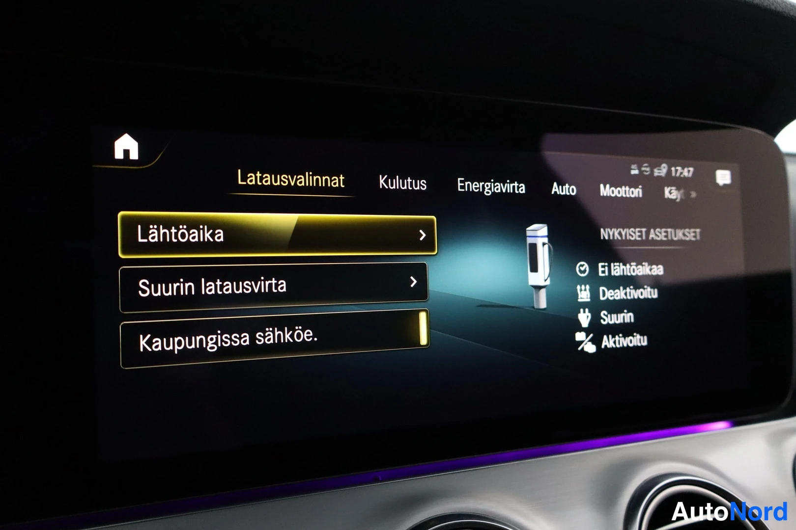 Yksityiskohta: Mercedes-Benzin centerpalkin infotainment-näyttö näyttää Latausvalinnat-valikon (Lähtöaika, Suurin latausvirta, Kaupungissa sähköe.) ja Energianhallinnan asetuk