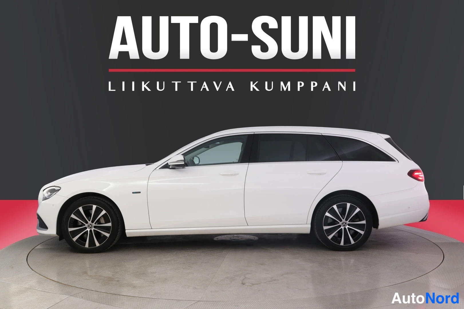 Sivulta: Valkoinen farmariauto sivusta kuvattuna, konepelti ja takaosan pyörä näkyvät.