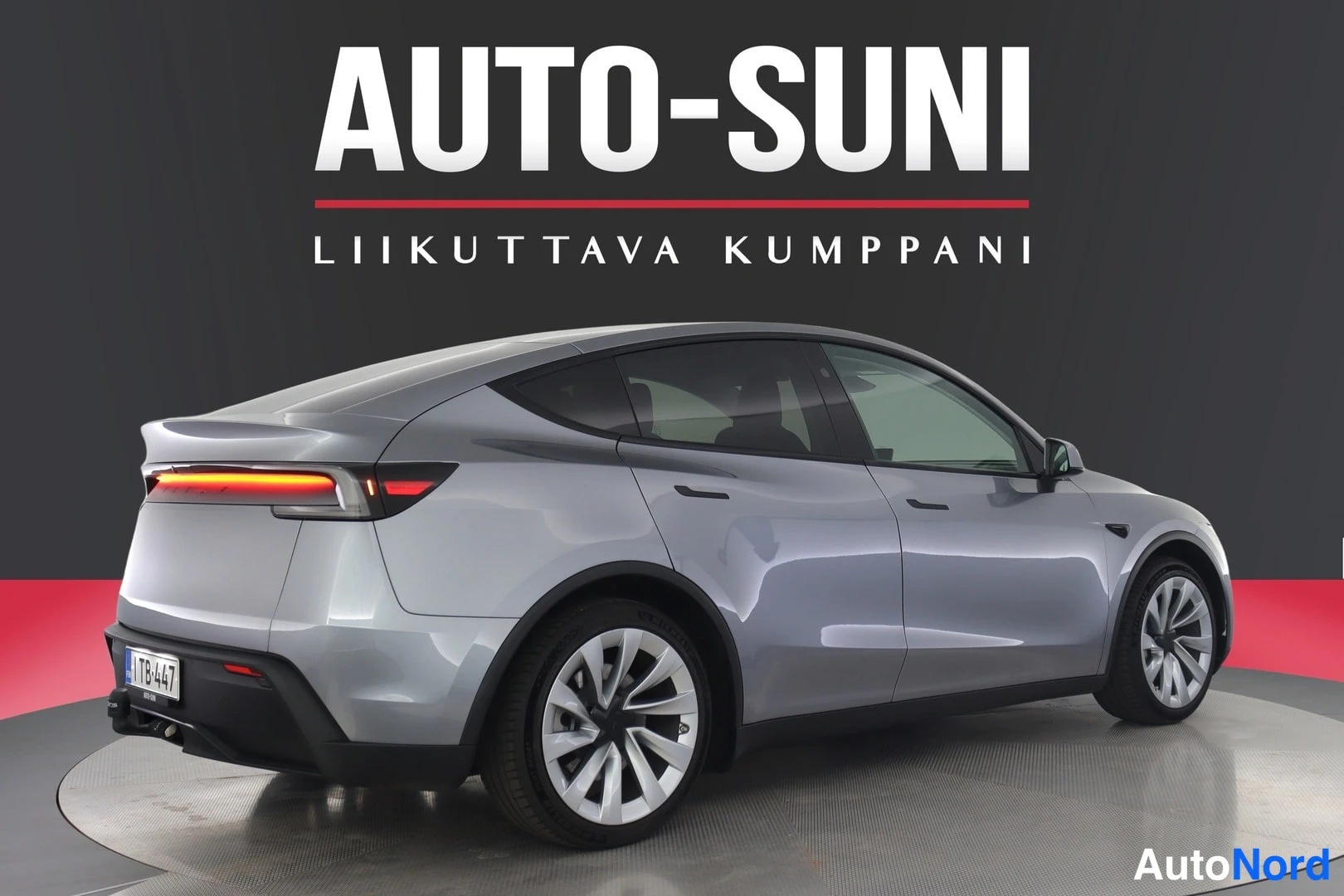 Takaviisto: Hopeanharmaa Tesla Model Y takakulmakuvassa, rekisterikilpi näkyvissä