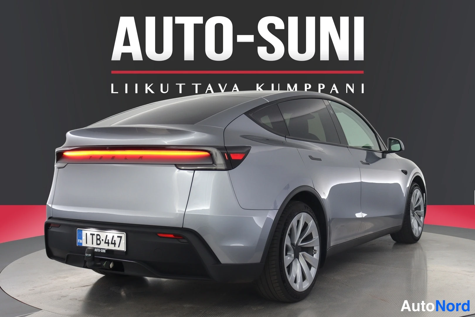 Takaviisto: Hopeanharmaa Tesla Model Y suora takaa sivusuunnasta kuvattuna, rekisterikilpi