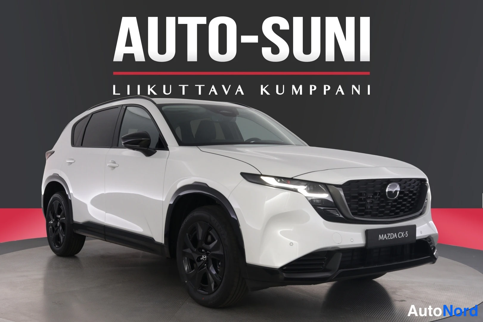 Etuviisto, nokka oikealle: Valkoinen Mazda CX-5 kuvattu kolmannelta edestä oikealta studioympäristössä mustalla taustalla ja AUTO-SUNI-logolla.