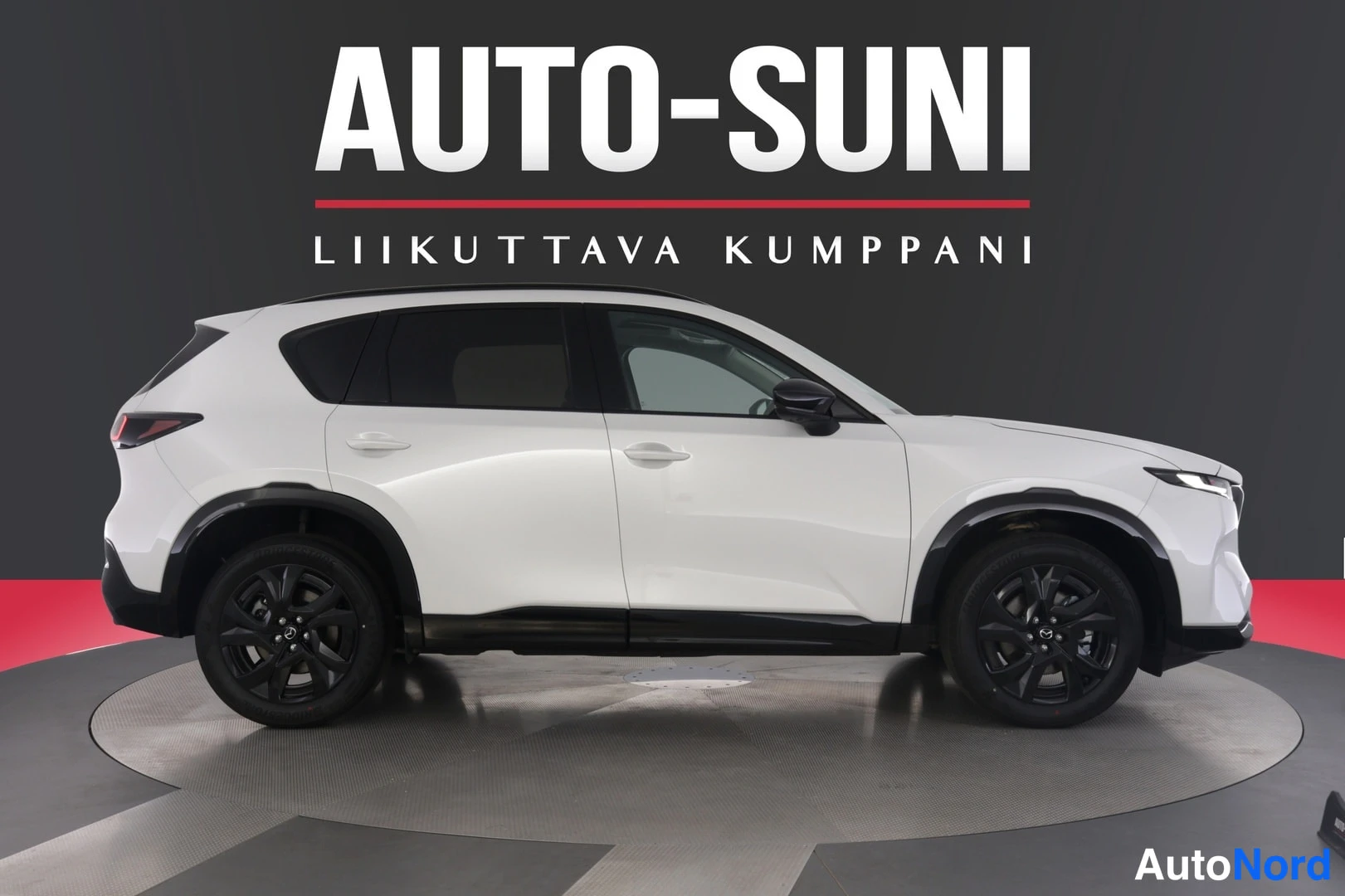 Sivulta: Valkoisen SUV-auton sivuprofiili, tummat kevytmetallivanteet ja mustat kivikilpensuojat, studiovalaistus mustalla taustalla.