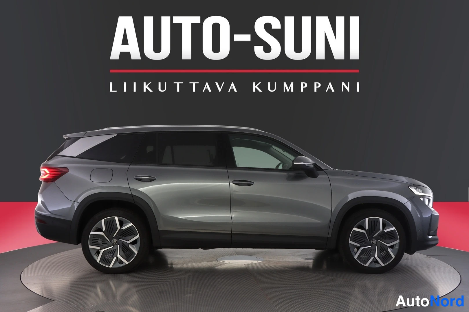 Sivulta: Tummanharmaan Skoda Kodiaq -maasturin sivukuva studyyli-taustaa vasten, molemmat kyljet ja pyörät näkyvät.