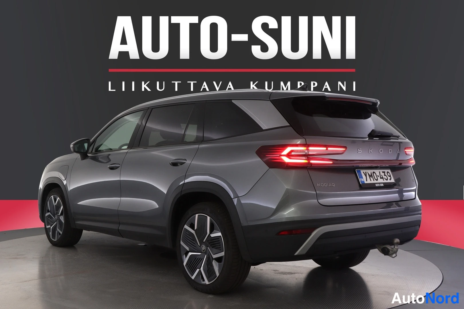 Takaviisto: Tummanharmaan Skoda Kodiaq -maasturin takakolmasosakuva studyyli-taustaa vasten, SKODA-taustakirjaimisto, KODIAQ-merkintä, takavalot, -rekisterikilpi ja vetokou