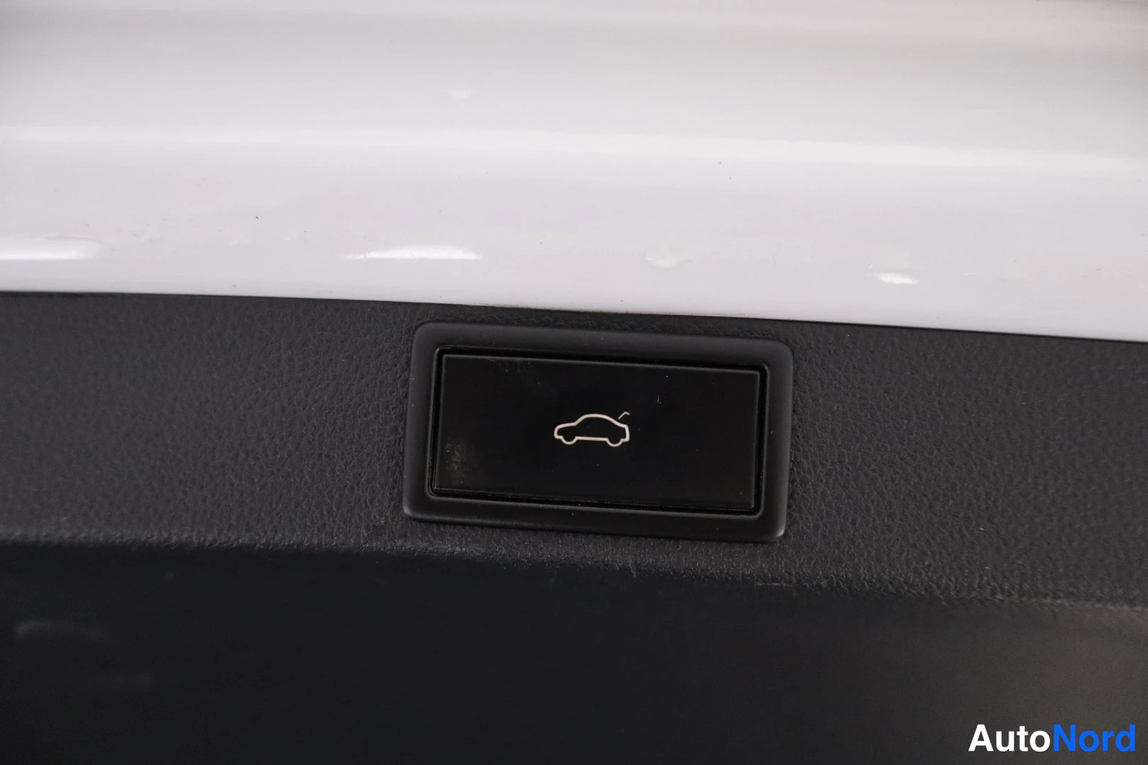 Yksityiskohta: Sähkötoiminen takaoven/tailgate-avainnappi autojen symbolilla mustassa panelissa.
