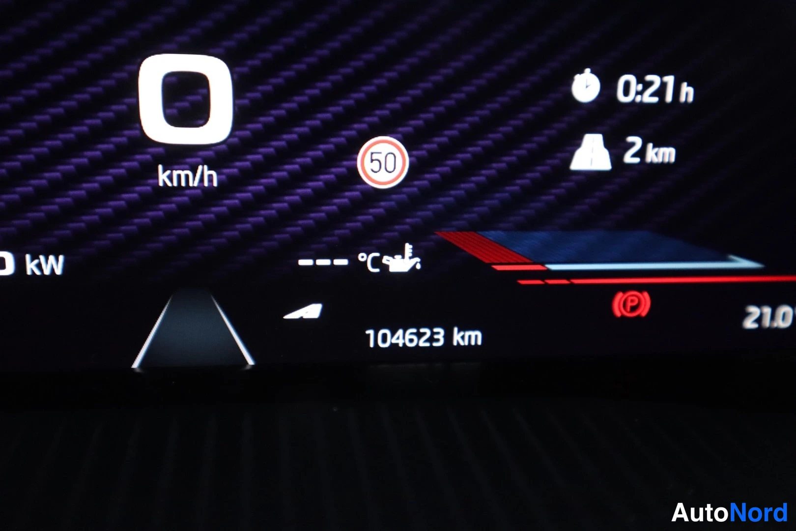 Yksityiskohta: Kojelauta näyttö: nopeus 0 km/h, rajoitus 50, matka 104623 km, 2 km tie, aika 0:21 h.