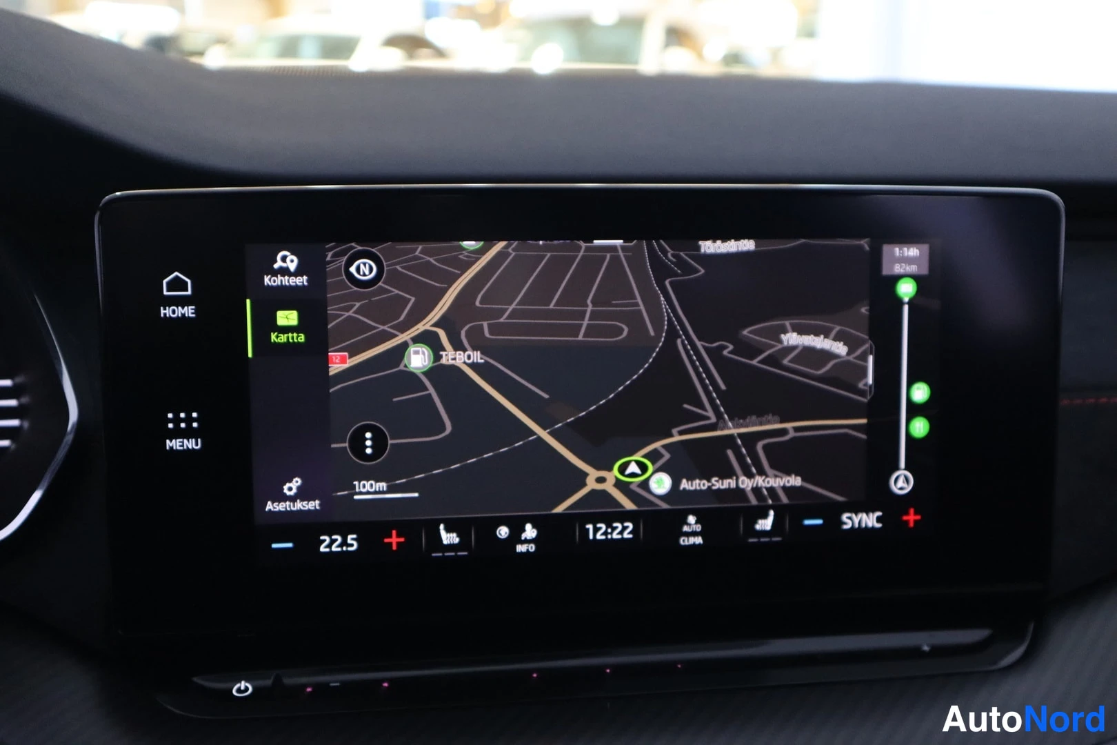 Yksityiskohta: Keskikonsolin infotainment-näyttö navigointikarttanäkymässä, karttaan on merkitty Auto-Suni Oy/Kouvola.