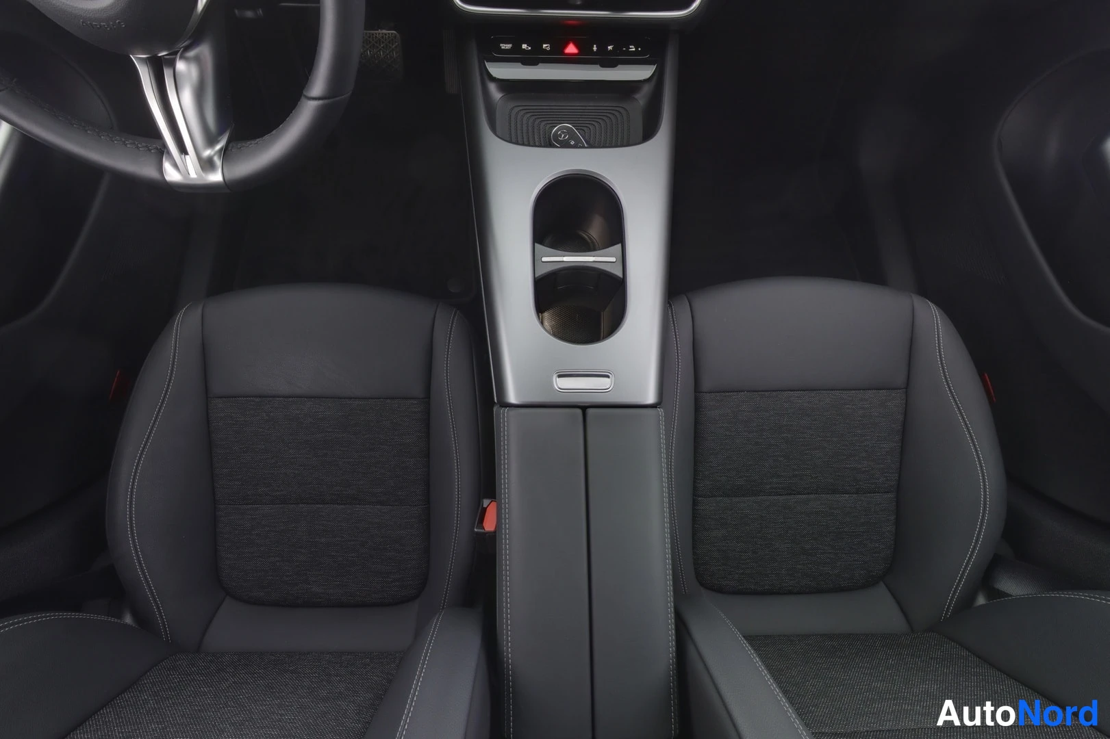 Etuistuimet: View of the front passenger and driver seats showing a two-tone interior with black leather on the bolsters and darker fabric in the center panels. The center c