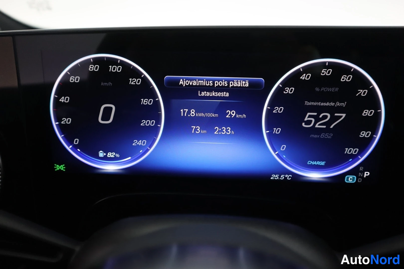 Yksityiskohta: Digital instrument cluster display illuminated in blue, showing the speedometer at 0 km/h. Center data reads 'Ajovalmius pois päältä' (Driving assistance off) f