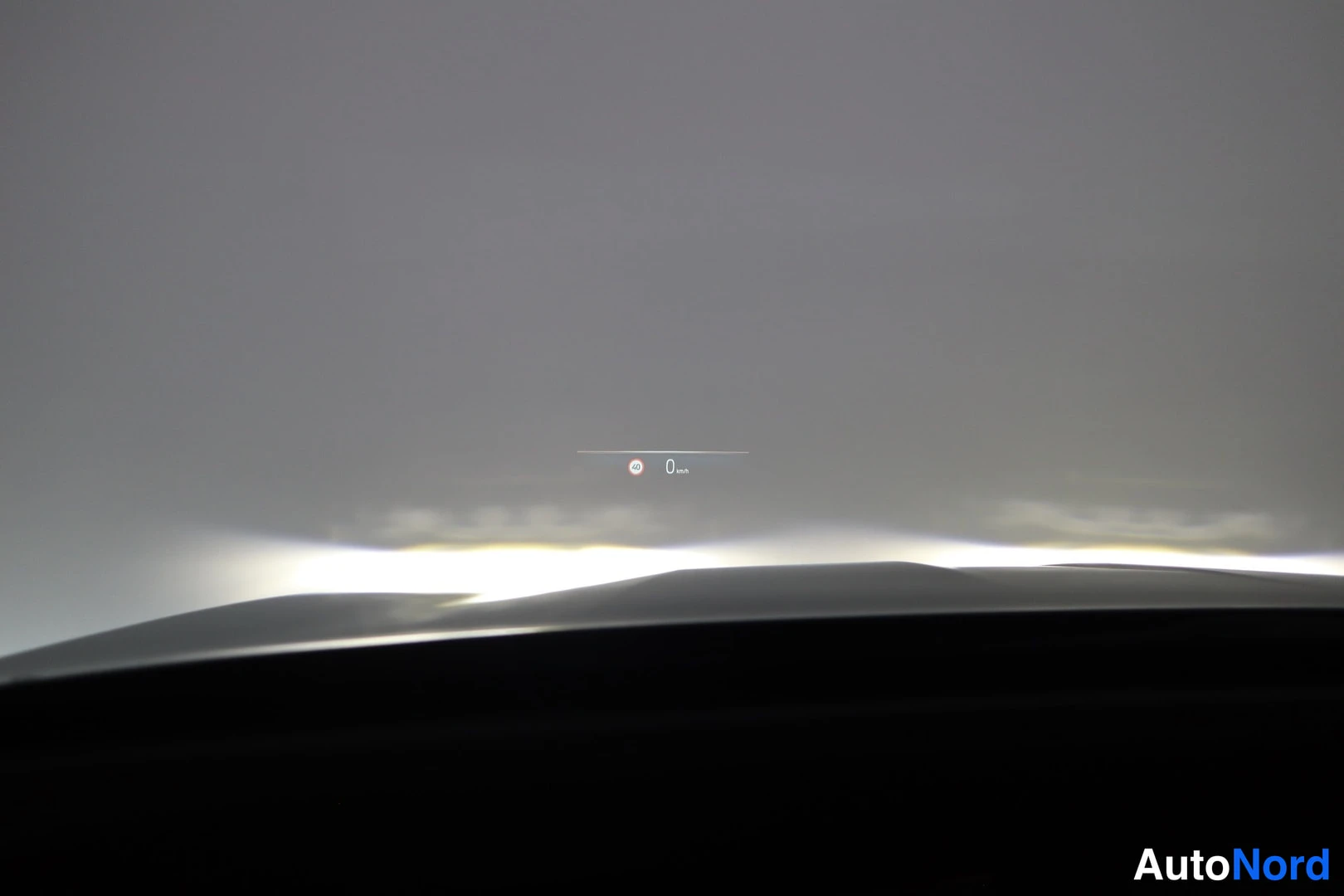 Yksityiskohta: Heijastuva HUD-näyttö tuulilasissa, jossa näkyy nopeus 0 km/h ja merkki 30.