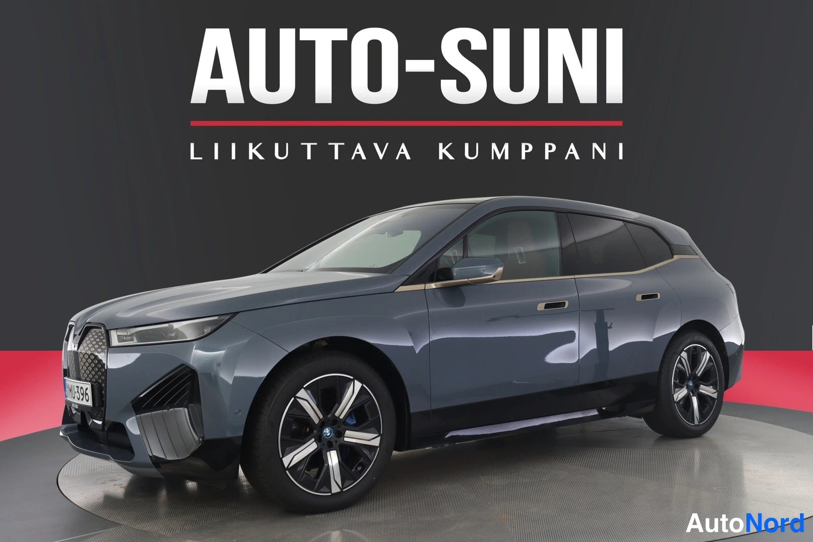 Etuviisto, nokka oikealle: Three-quarter view of a blue BMW iX electric SUV from the left rear.