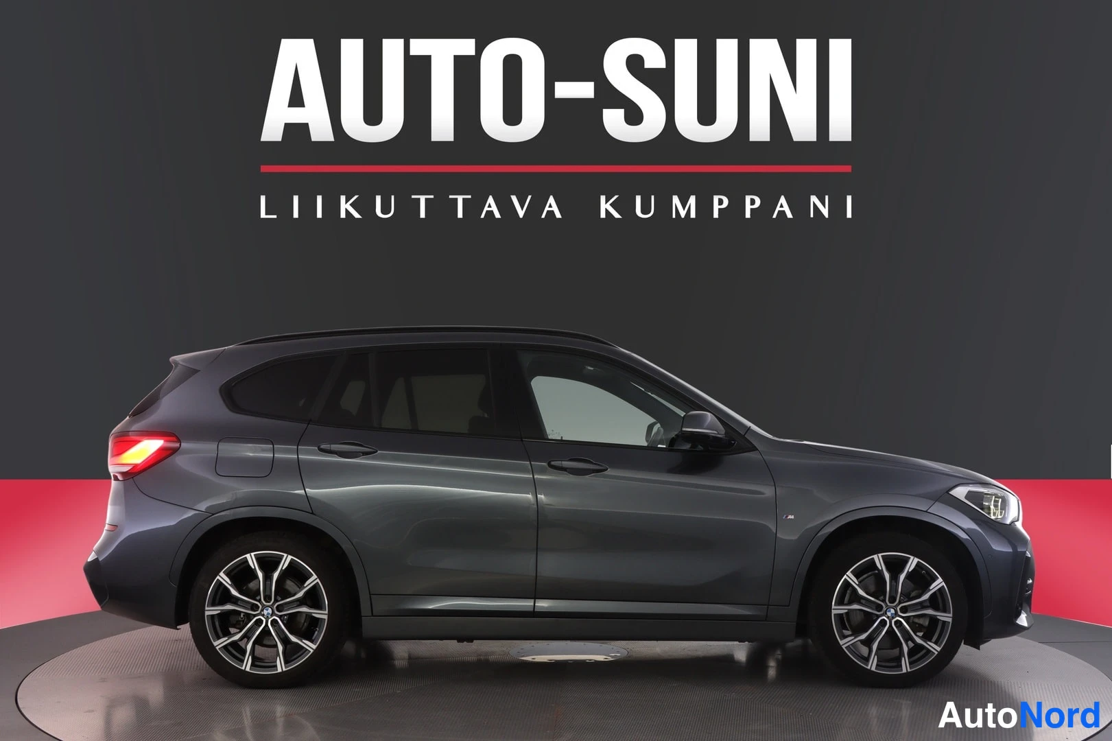 Sivulta: Auton kylki täysin sivulta, tummanharmaa koripinta, viisiovinen malli vaa'ankulmataustaa vasten.