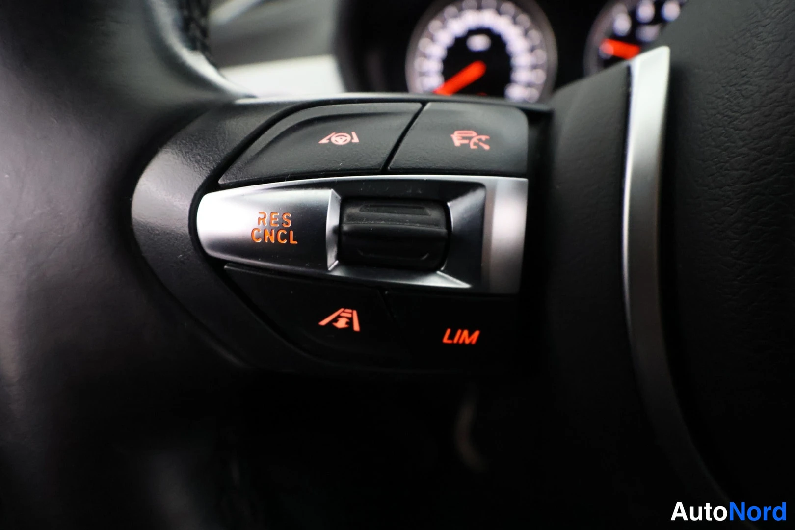 Yksityiskohta: Left steering wheel control stalk buttons for cruise control including RES, CNCL, LIM, speed adjustment icons.