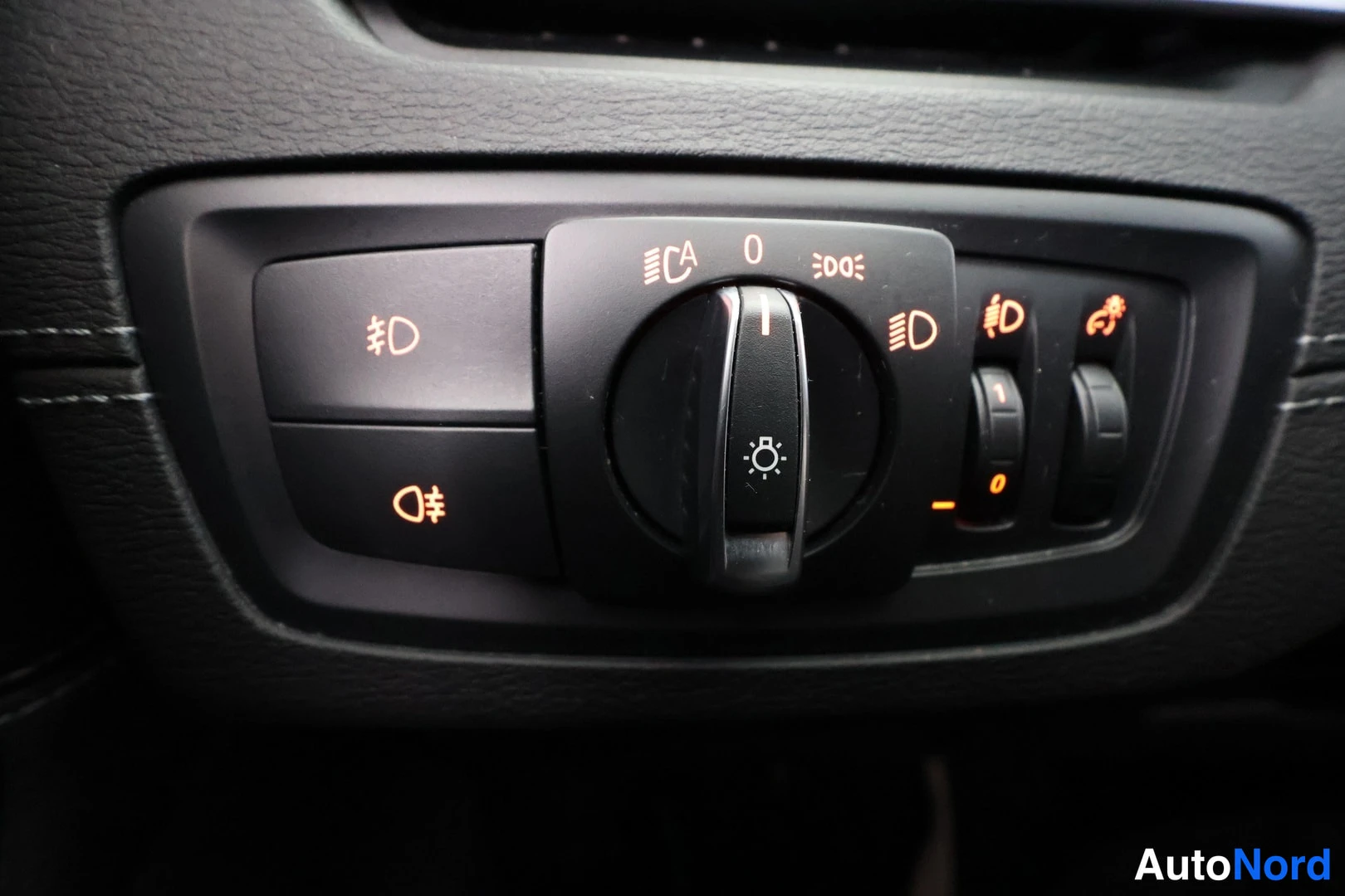 Yksityiskohta: Headlight control switch panel with rotary selector in '0' position flanked by buttons for fog lights and automatic high beams.