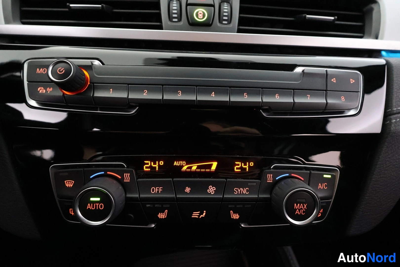 Ohjaamo: Close-up view of the car's center console showing climate and media controls. The dual-zone automatic climate control display reads '24° AUTO' on both sides, wi