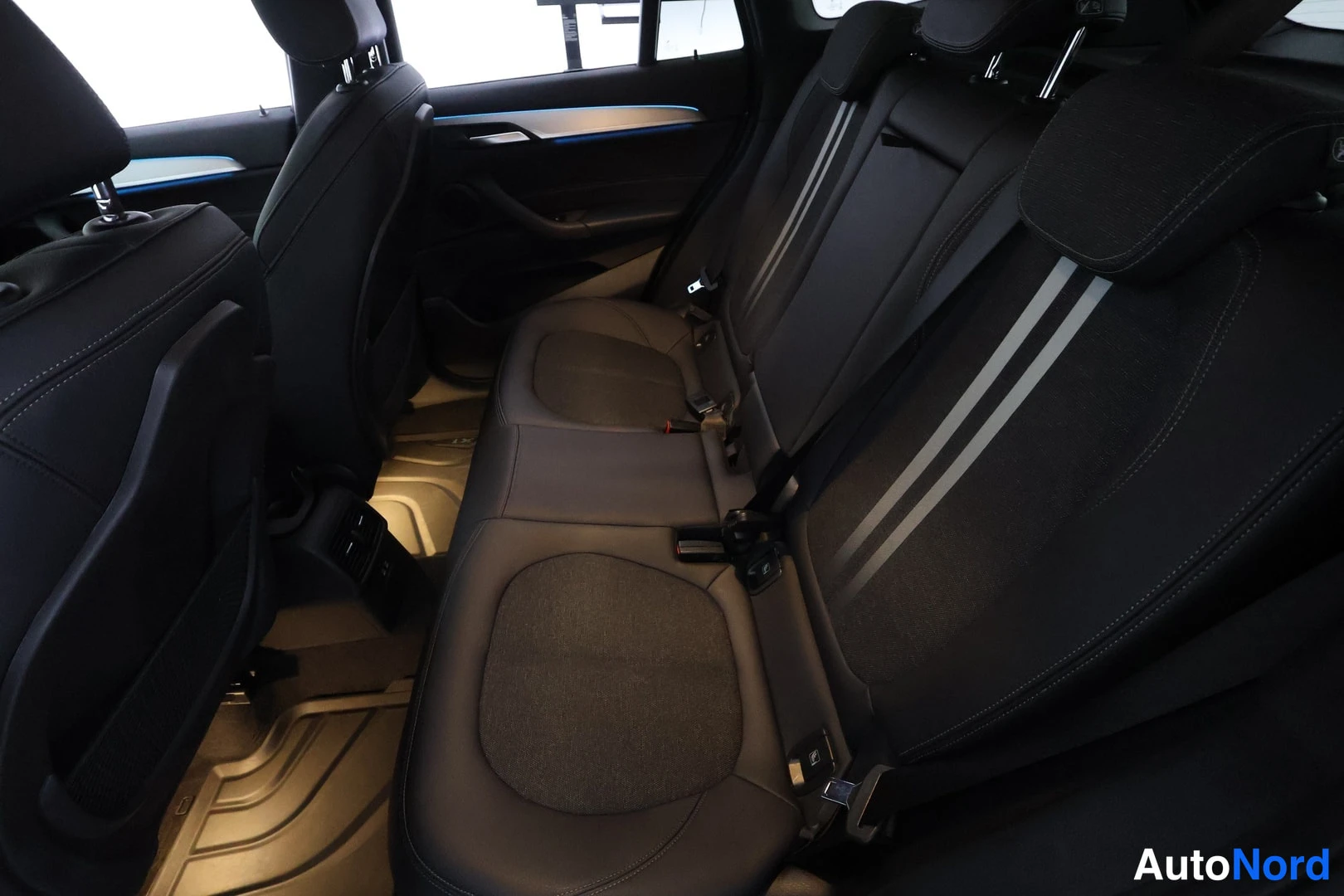 Takaistuimet: Interior view of the rear seating area featuring two individual rear seats upholstered in black material with grey fabric inserts on the seat cushions and backs