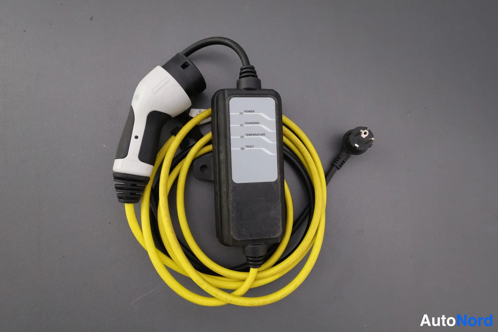 Yksityiskohta: Sähköauton laturin kaapelisetti: keltainen kaapeli, valkomusta latauspistoke, Schuko-pistoke ja musta ohjelaite, jonka merkkivalot POWER, CHARGING, TEMPERATURE