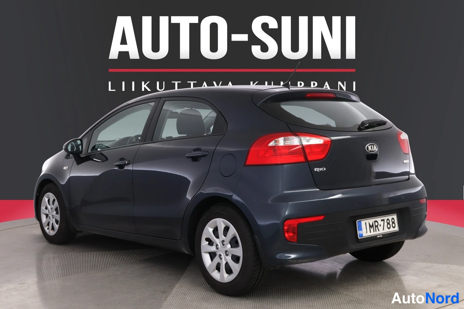 Takaviisto: Tummanharmaan Kia Rio -viistoperän takaosa ja vasen kylki kuvattuna, rekisterillä.