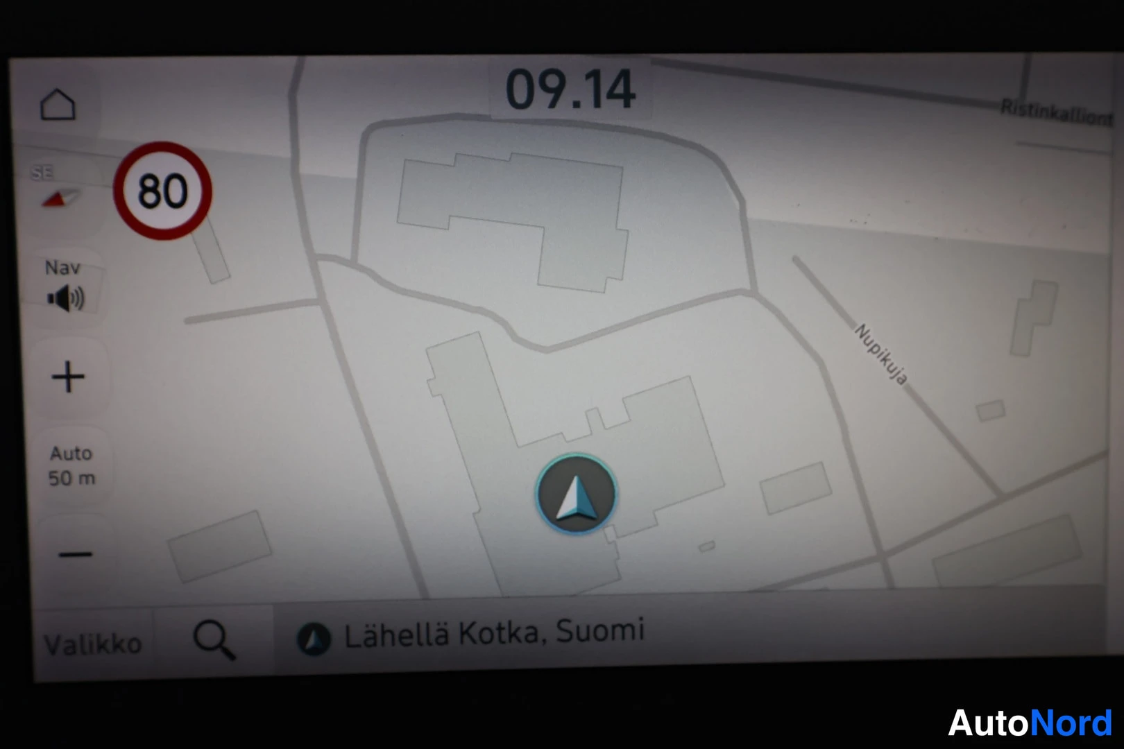 Yksityiskohta: Auton infotainment-näytön lähikuva: karttanäkymä, jonka alareunassa lukee »Lähellä Kotka, Suomi». Näytön yläreunassa kello 09.14, vasemmalla nopeusrajoitusmerkk