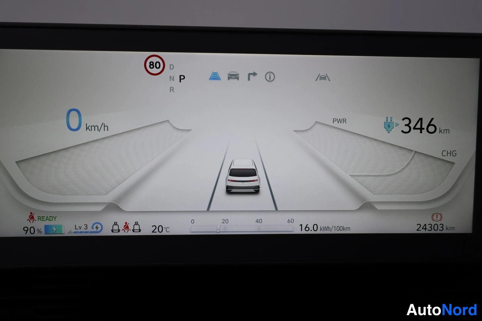 Ohjaamo: Lähikuva auton digitaalisesta mittaristosta. Mittari näyttää nopeuden 0 km/h ja kulutetun energian. Mittariston värit ovat pääasiassa valkoiset, keltaiset, sini