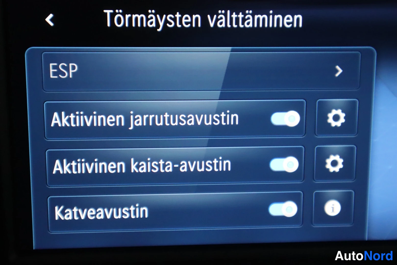 Ohjaamo: Dashboard display showing the safety settings menu titled Törmaysten välttäminen (Collision Avoidance). Options displayed include ESP, Aktiivinen jarrutusavusti