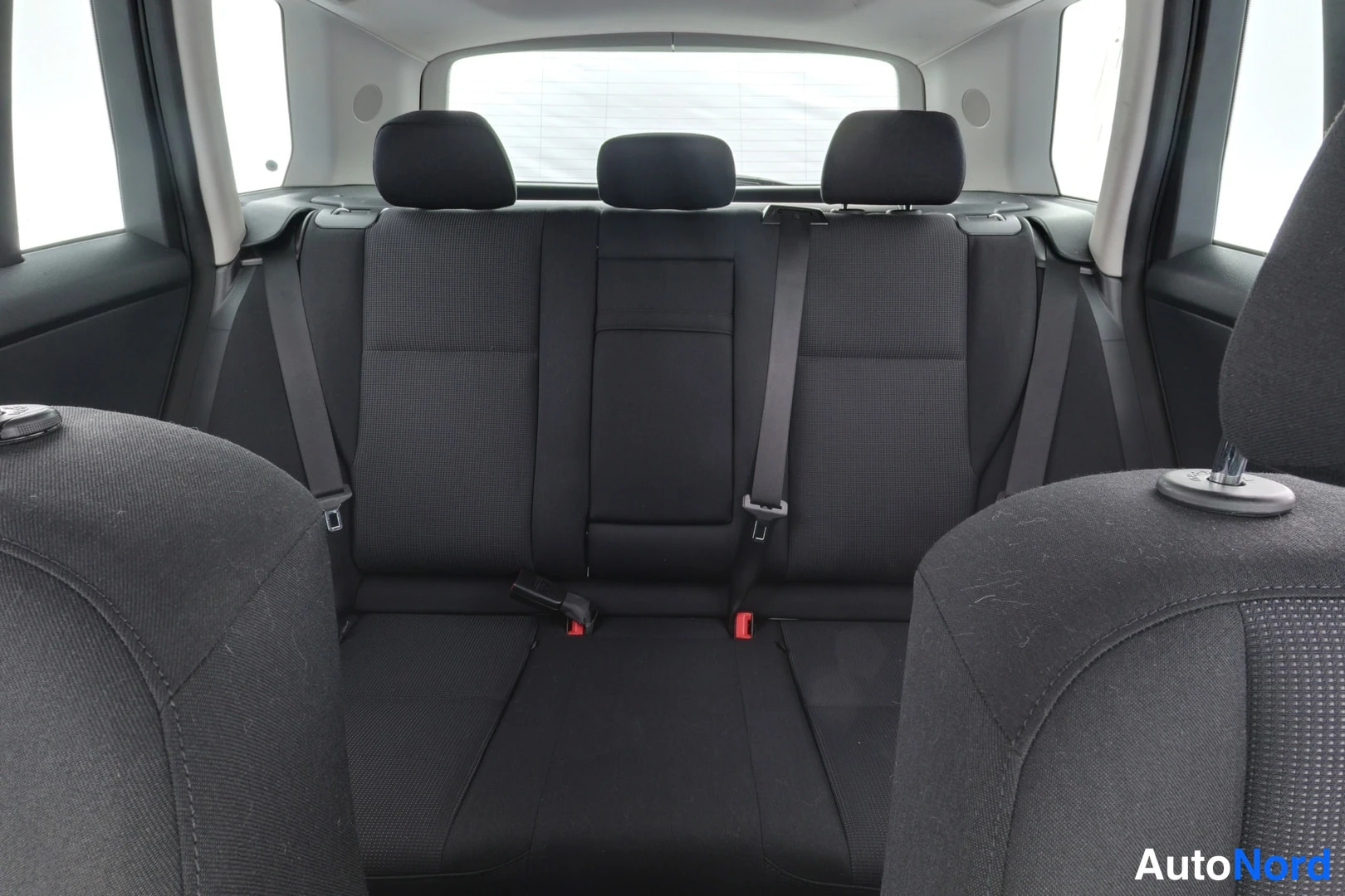 Takaistuimet: Black fabric rear bench seat with three headrests viewed from inside the cabin