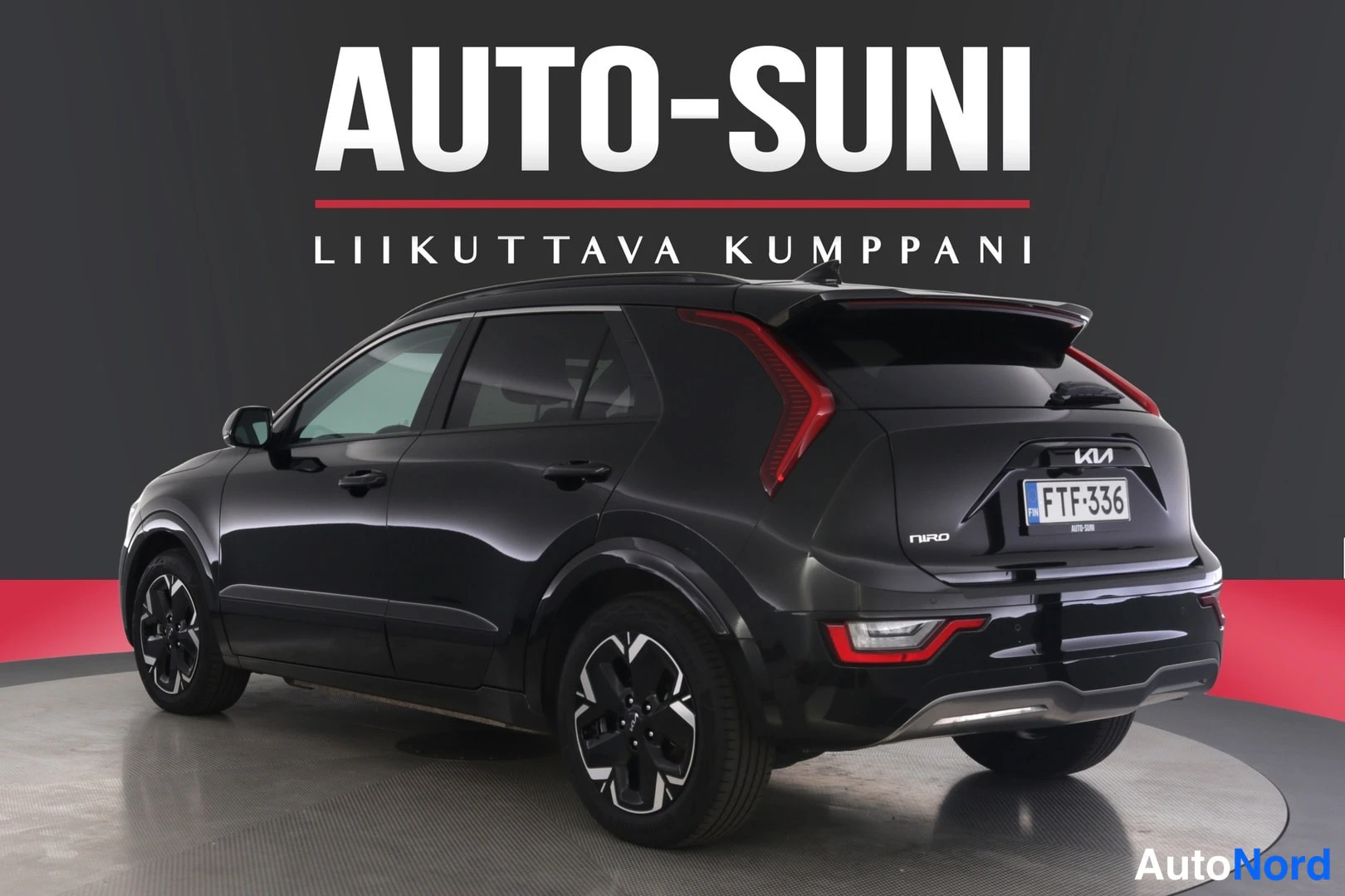 Takaviisto: Musta Kia Niro kuvattuna vinosti takaa, perä kuvan oikeassa reunassa, rekisteritunnus.