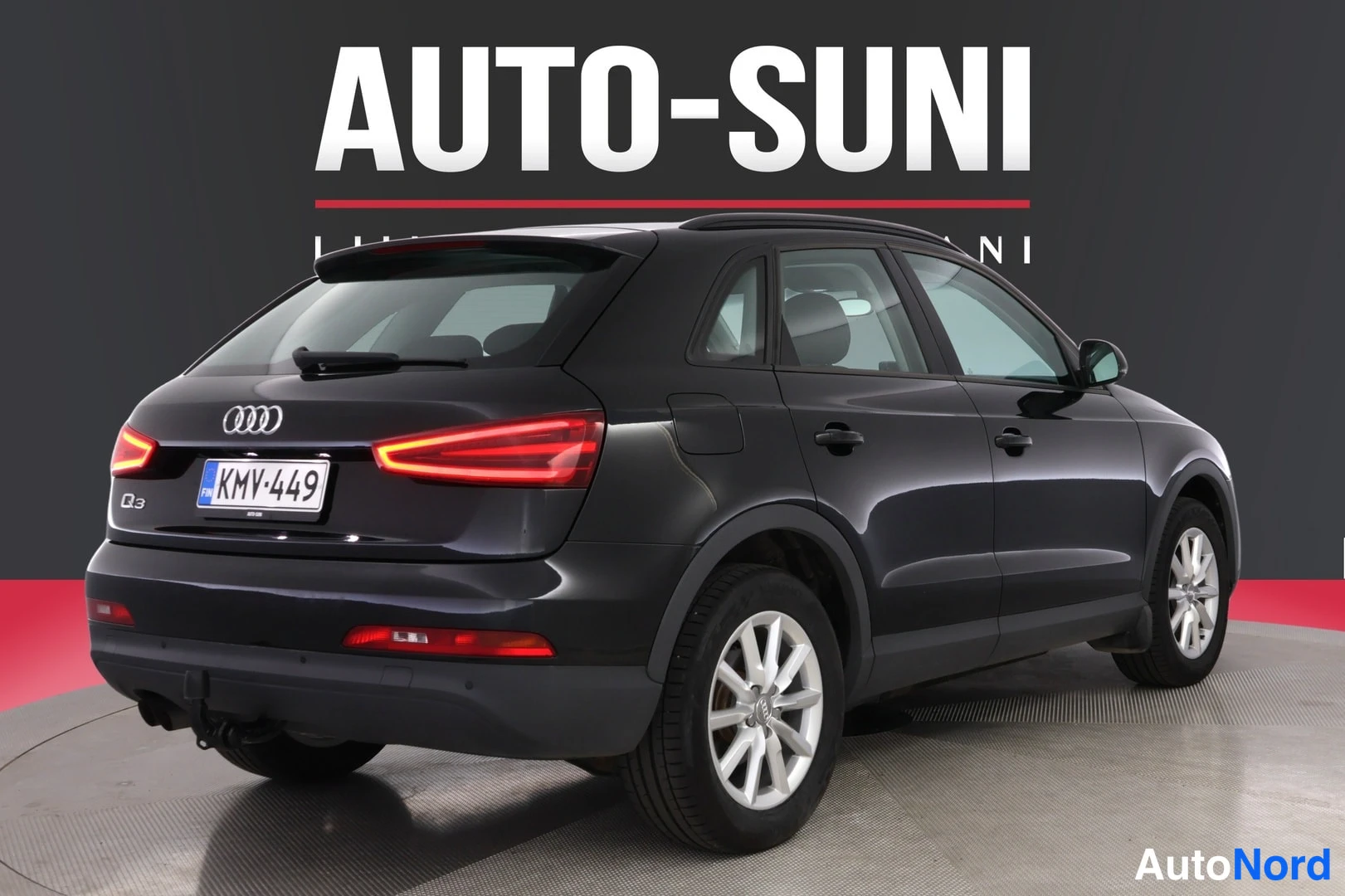 Takaviisto: Musta Audi Q3 -maast_auto etuosoalta oikeaan alakulmaan kääntyneenä studiotaustaa vasten, rekisteritunnus, valkoiset vanteet ja AUTO-SUNI mainosteksti taustalla