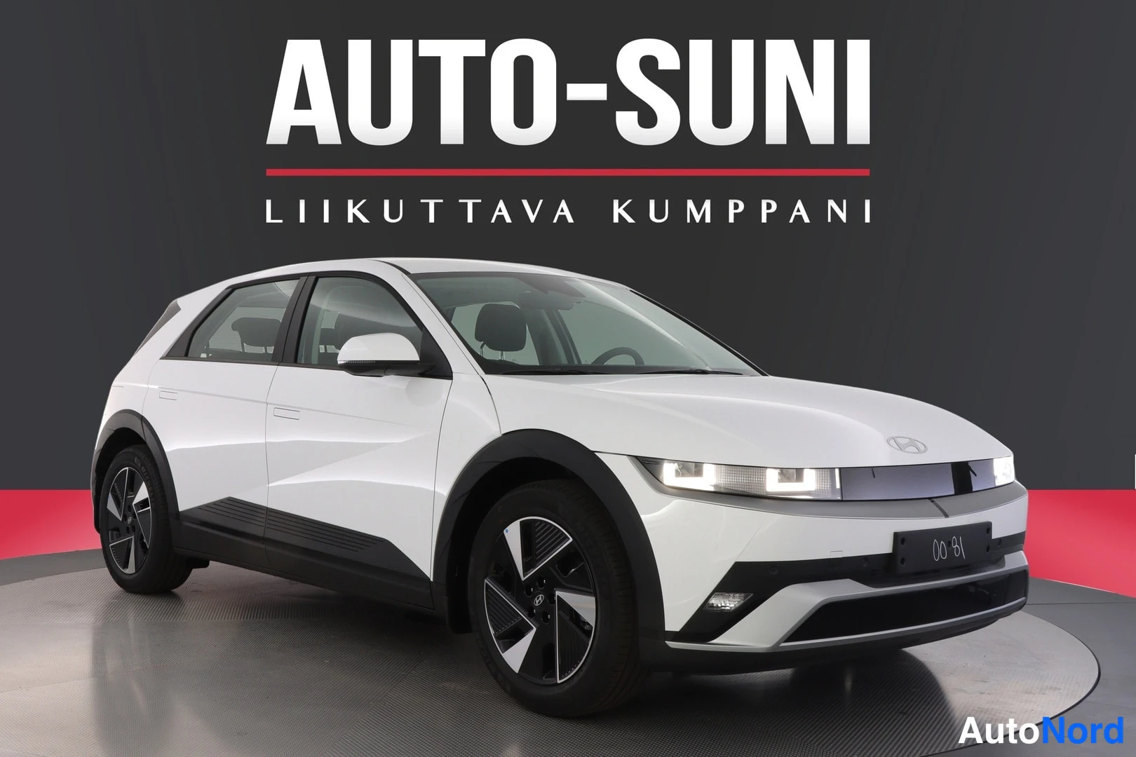 Etuviisto, nokka oikealle: Valkoinen Hyundai IONIQ 5 etuviistosta oikealle kuvattuna studiotaustaa vasten, jakoavaimet-kaavio maalattuna kylkiin.