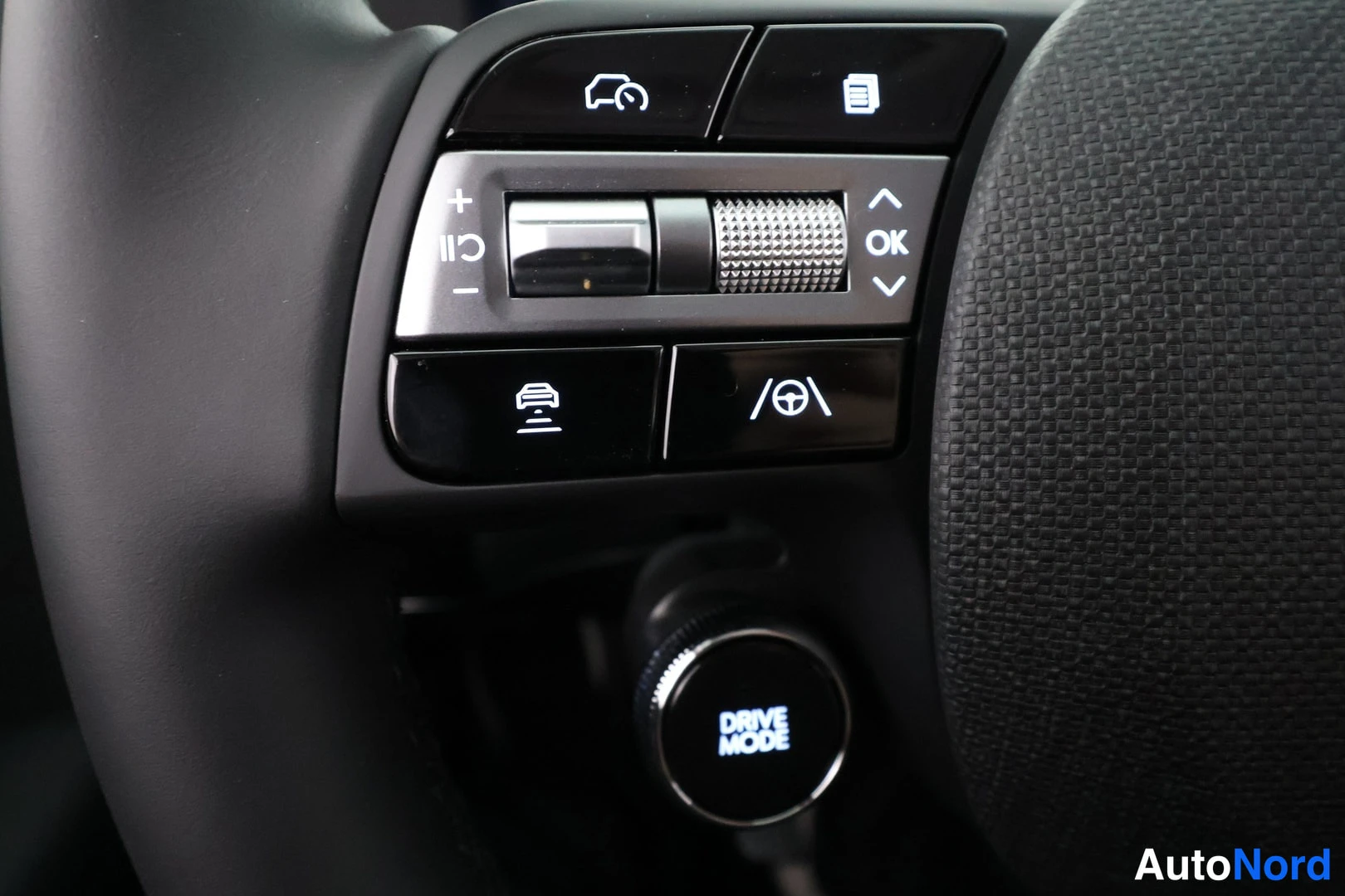 Yksityiskohta: Ohjauspyörän käyttöpainikkeet ja DRIVE MODE -nupp lähikuvassa.
