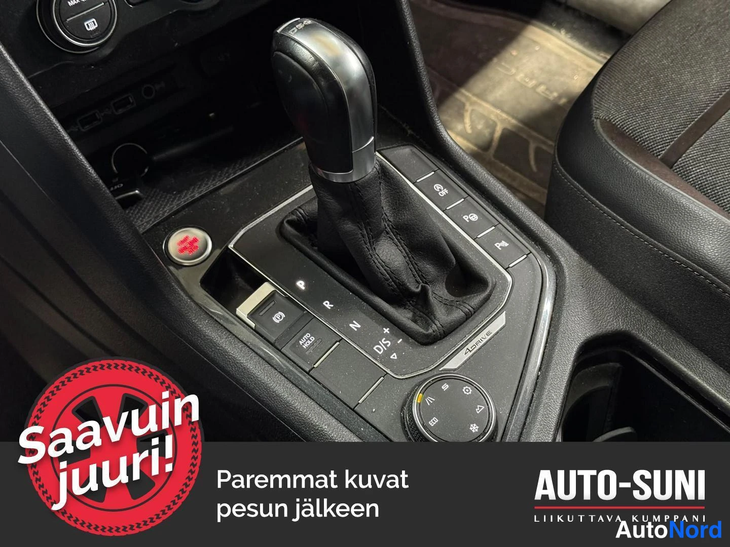 Yksityiskohta: Automaattivaihteenvalitsin ja keskikonsolin napit maton päällä