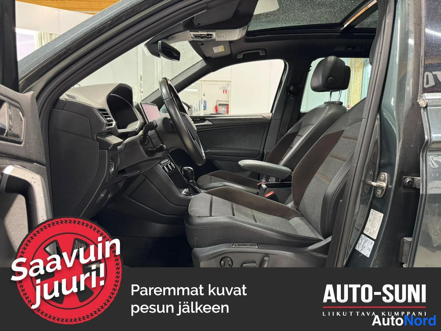 Muu: Auton sisätilat etupenkeiltä nähtynä: tummat kangas-nahkaverhoillut istuimet, ohjauspyörä ja kokoava lasikatto, vasemmanpuoleinen etuovi auki.