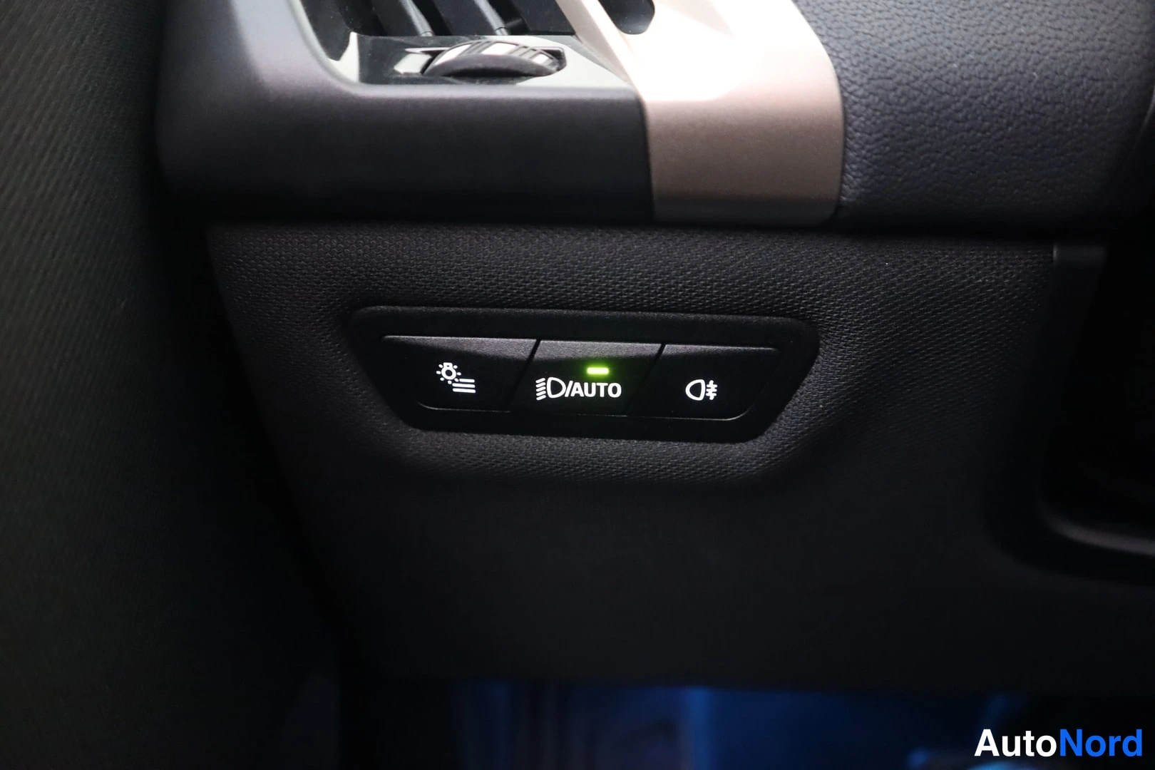 Yksityiskohta: Auton kojelaudan valokytkinpaneeli, jossa AUTO-tila merkitty vihreällä valolla.