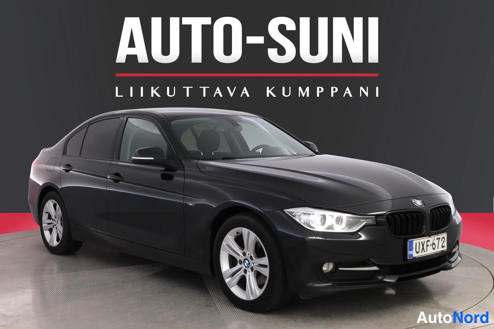 Etuviisto, nokka oikealle: Musta sedan etukulmasta oikealta, tummassa studiossa, Autotuni-logo taustalla.