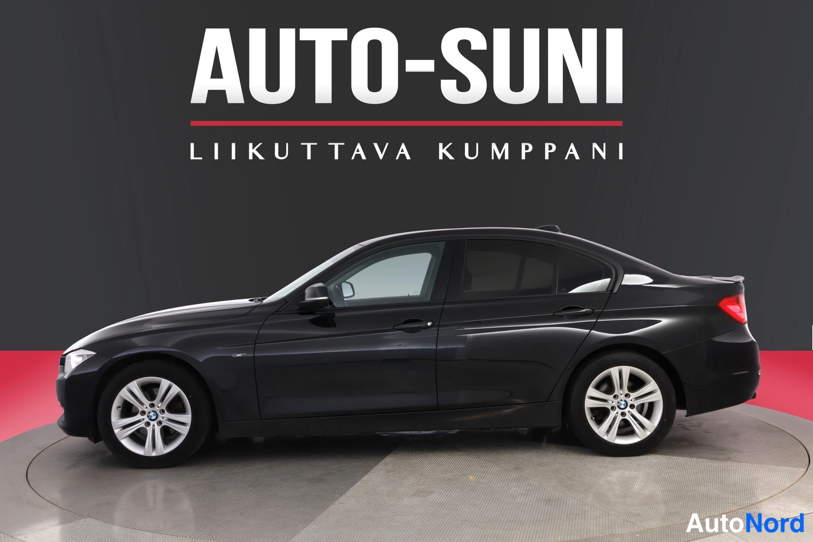 Sivulta: Mustan BMW 3-sedan sivuprofiili studiotaustaa vasten, keula vasemmalla.