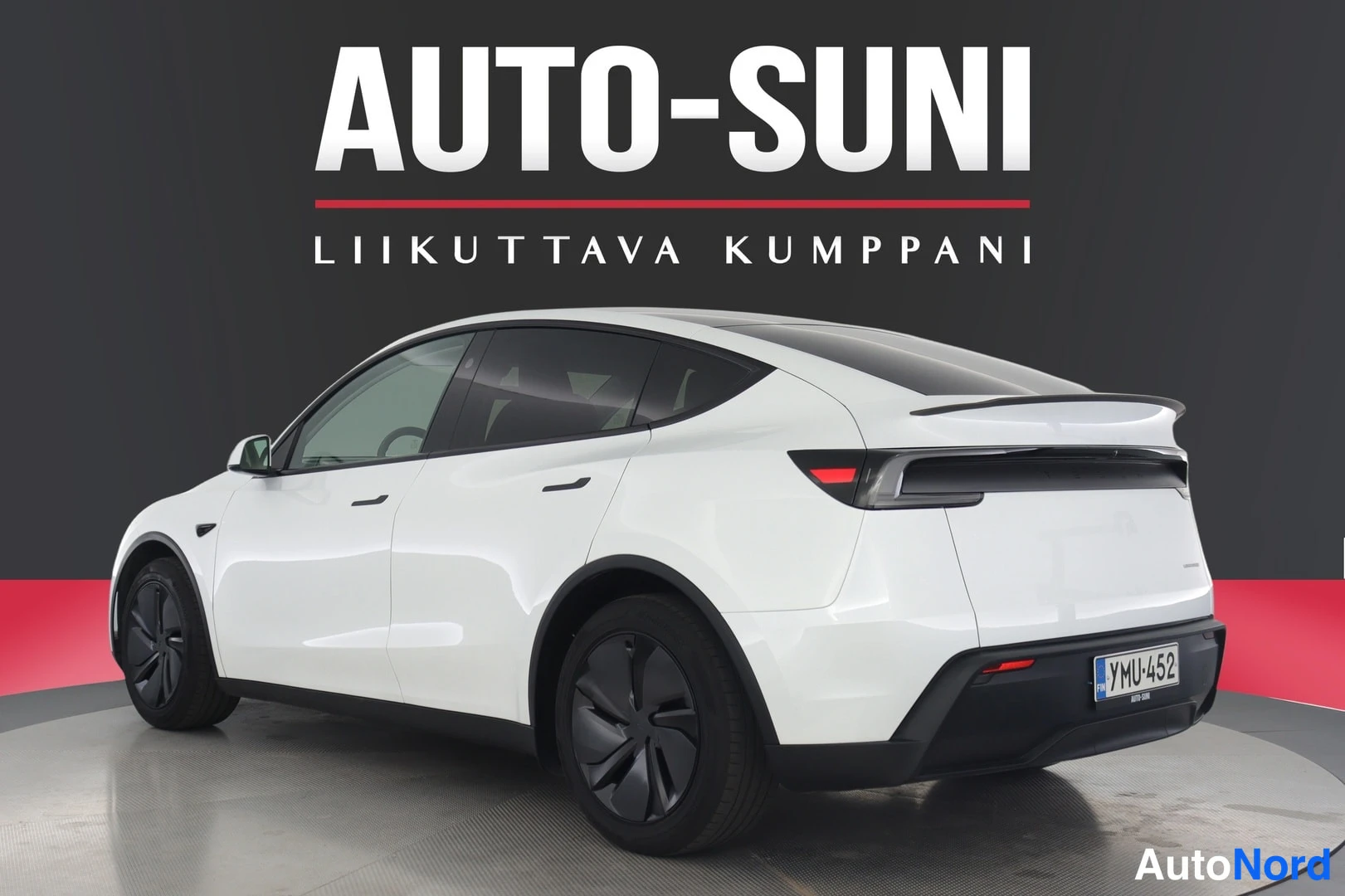 Takaviisto: Valkoinen Tesla Model Y takaa kolmesta neljännestä oikealta, takaosan ja kylkien näkyessä.