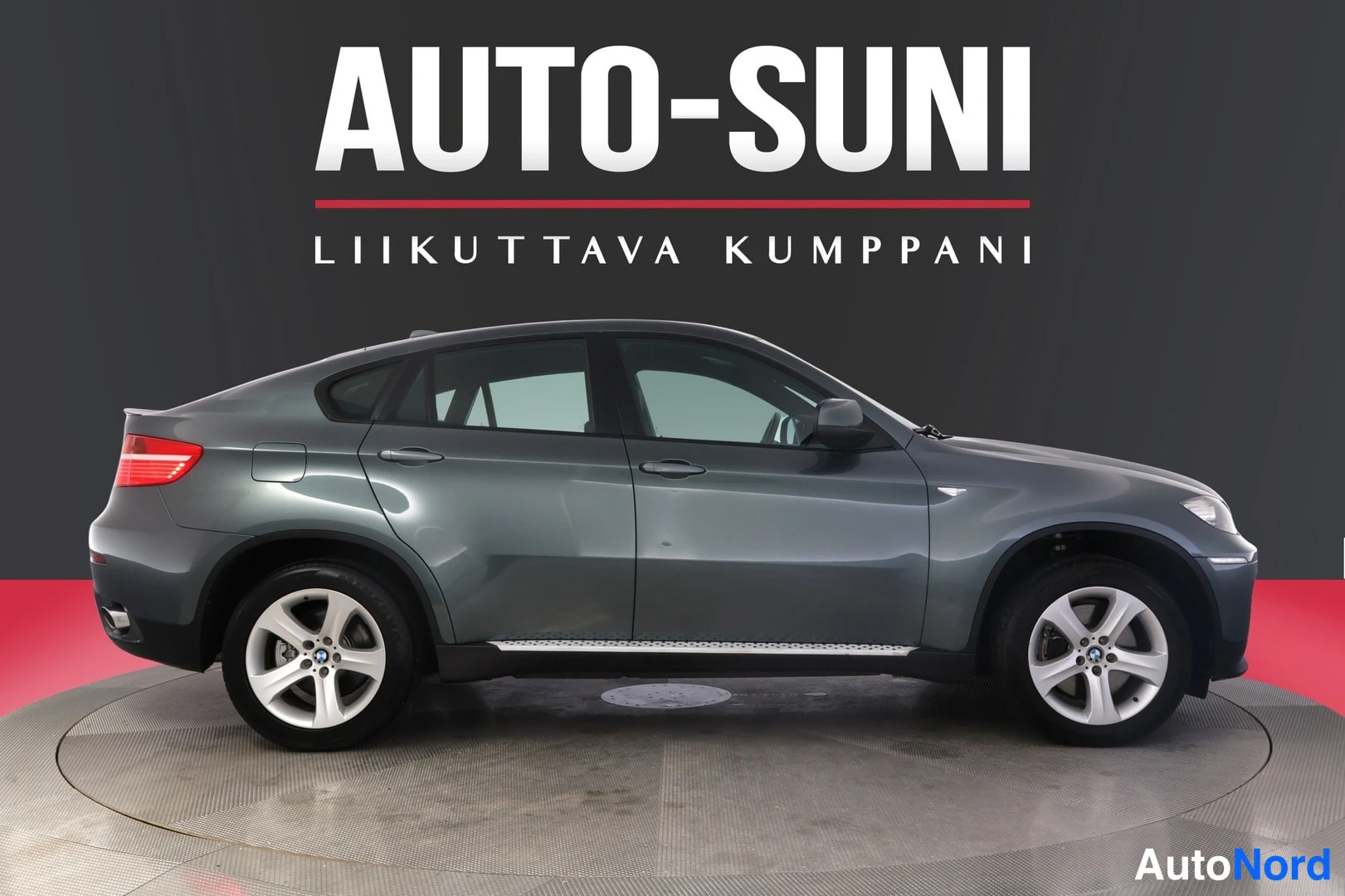 Sivulta: Sivukuvassa tummanharmaa BMW X6 -maasturiAutosunin studiotaustaa vasten.